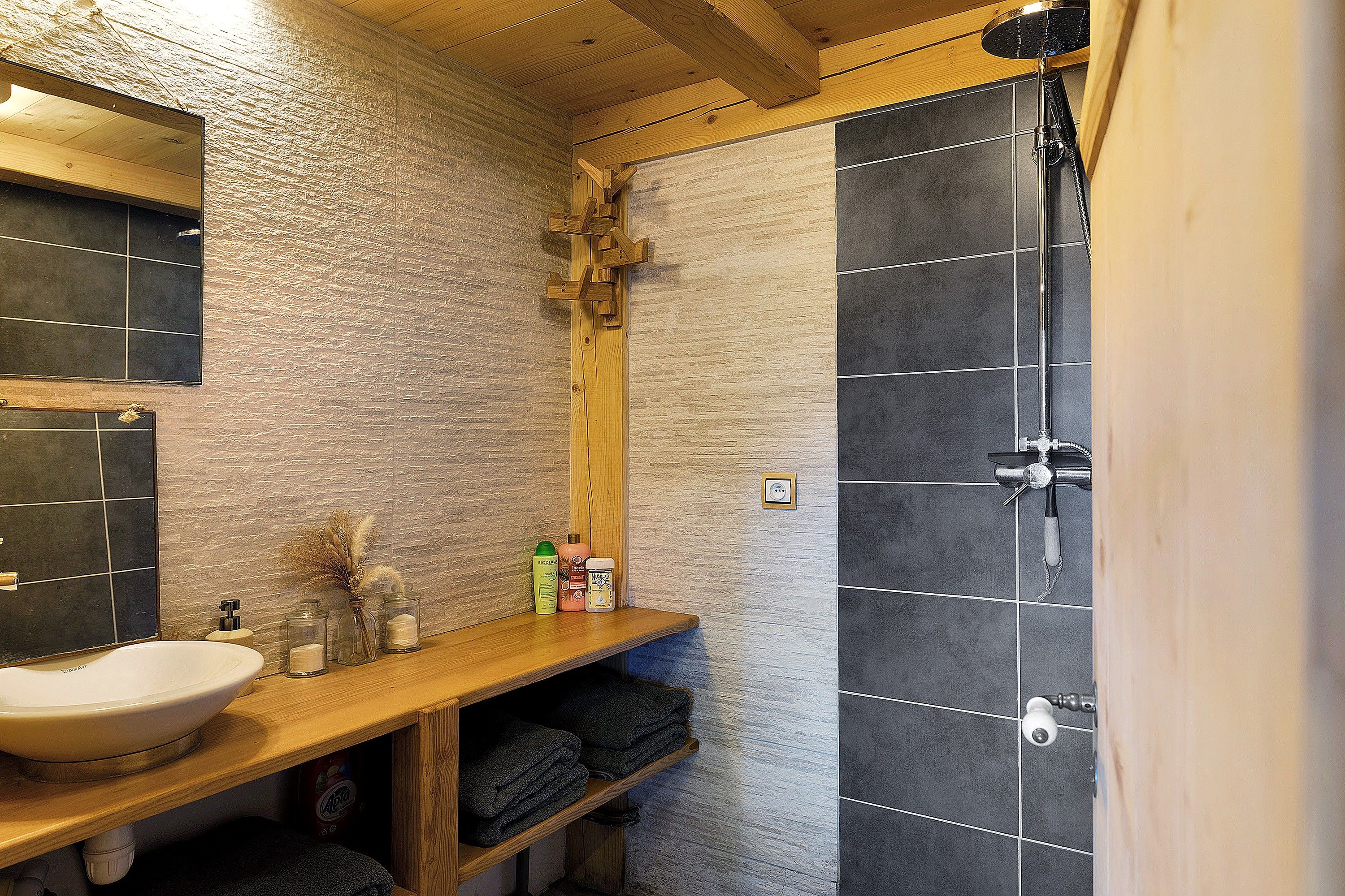 Un bagno con un mobile lavabo in legno, un lavandino e uno spazio doccia.