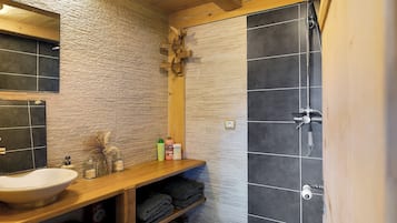 Un bagno con un mobile lavabo in legno, un lavandino e uno spazio doccia.