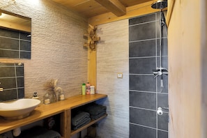 Un bagno con un mobile lavabo in legno, un lavandino e uno spazio doccia.