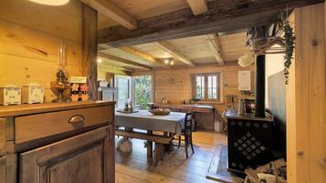 A rustic wooden interior with a dining area, wooden cabinets, and a traditional stove.