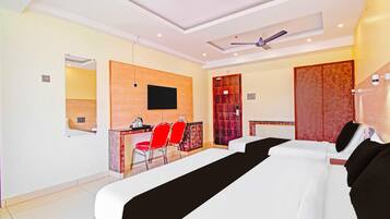 A hotel room with a large bed, a desk with a chair, a television, and a ceiling fan.