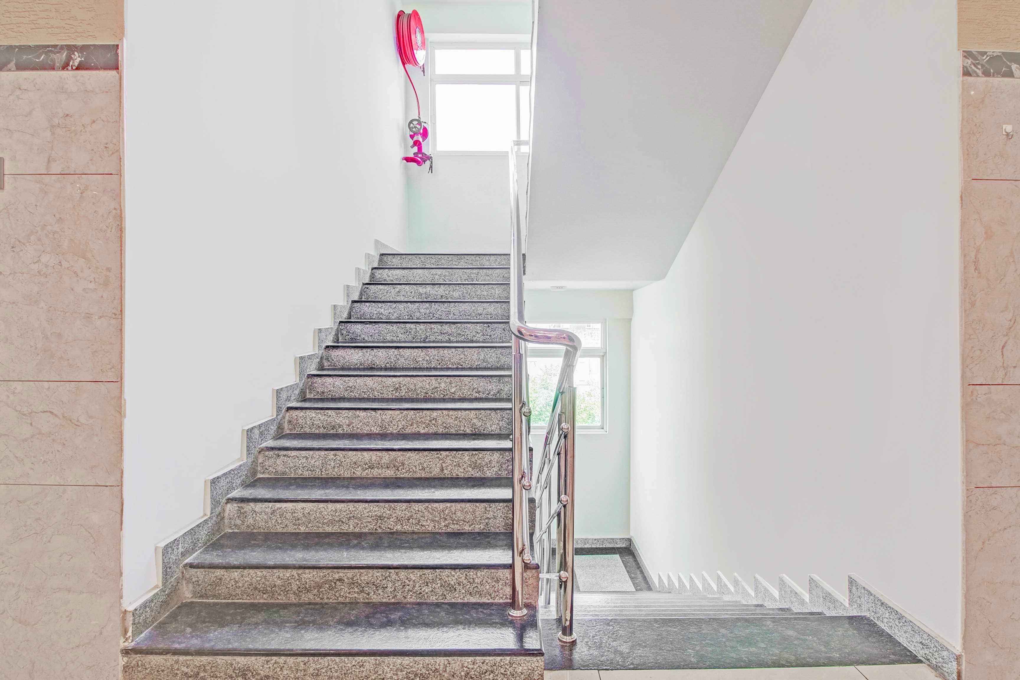 Una escalera con barandilla que lleva a un rellano con ventana.