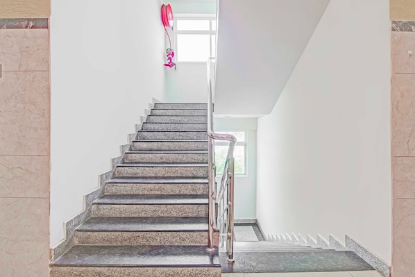 A staircase with a handrail, leading to a landing with a window.