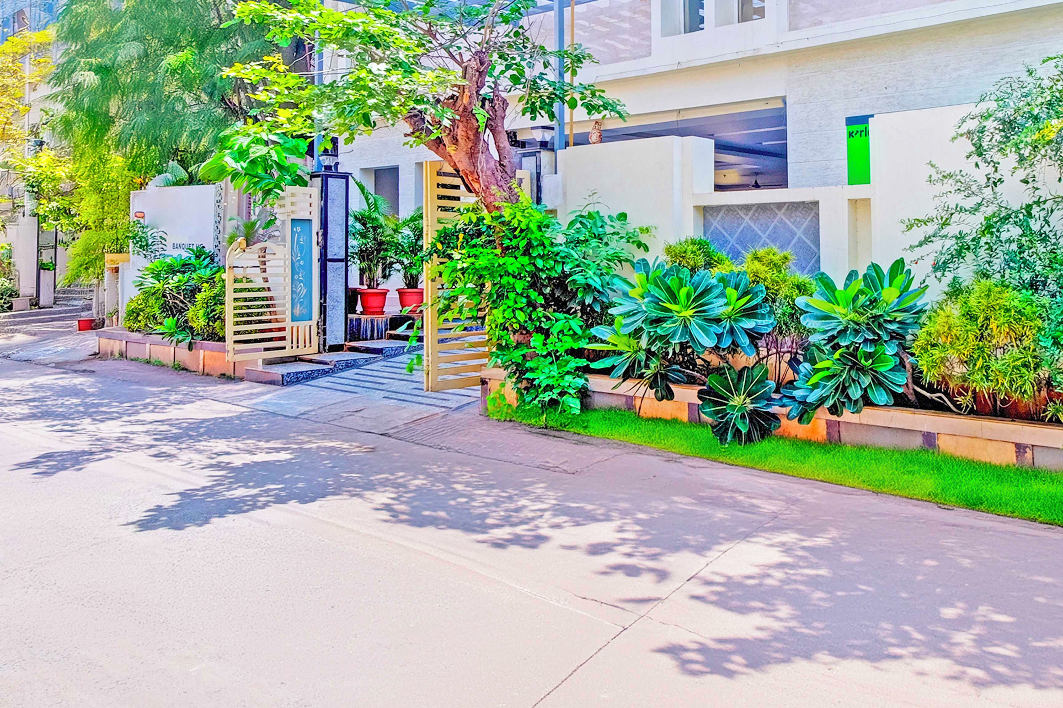 A residential street with modern houses, a gated entrance, and lush greenery.