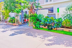 Una calle residencial con casas modernas, un acceso con portón y abundante vegetación.
