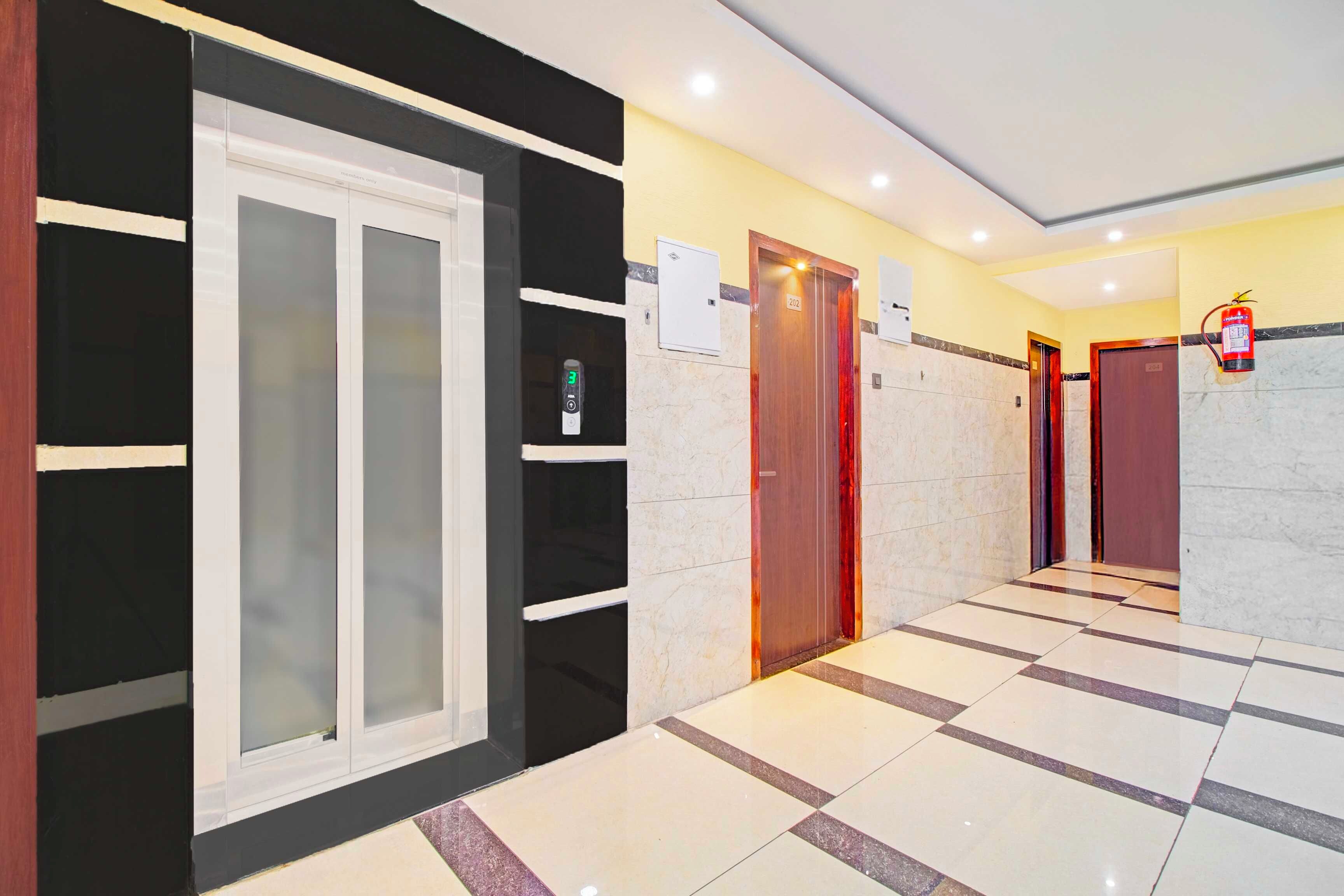 A hotel lobby with a modern design, featuring a check-in counter, a reception desk, and a fire extinguisher mounted on the wall.