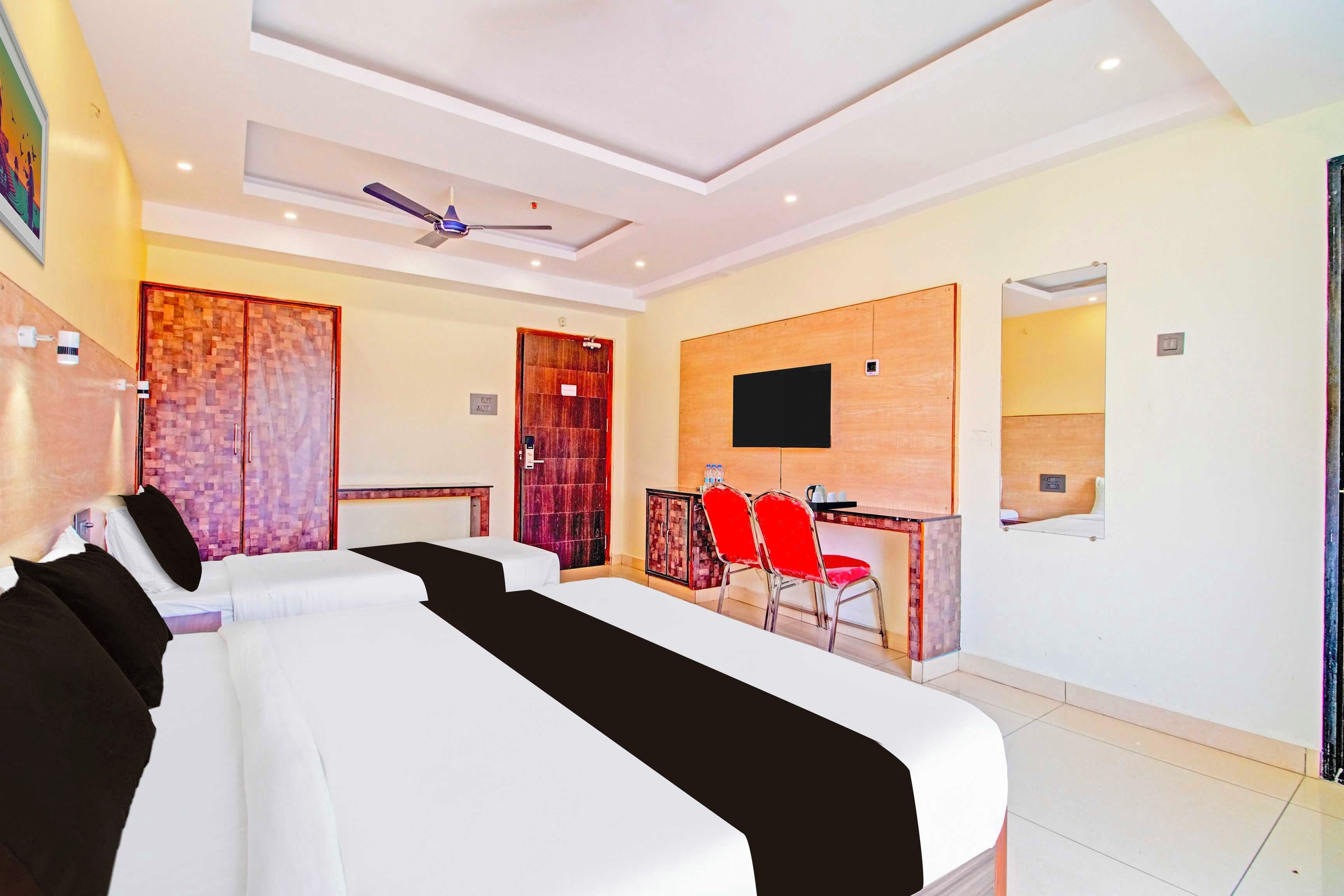 A hotel room with a bed, a desk, a chair, a television, and a ceiling fan.