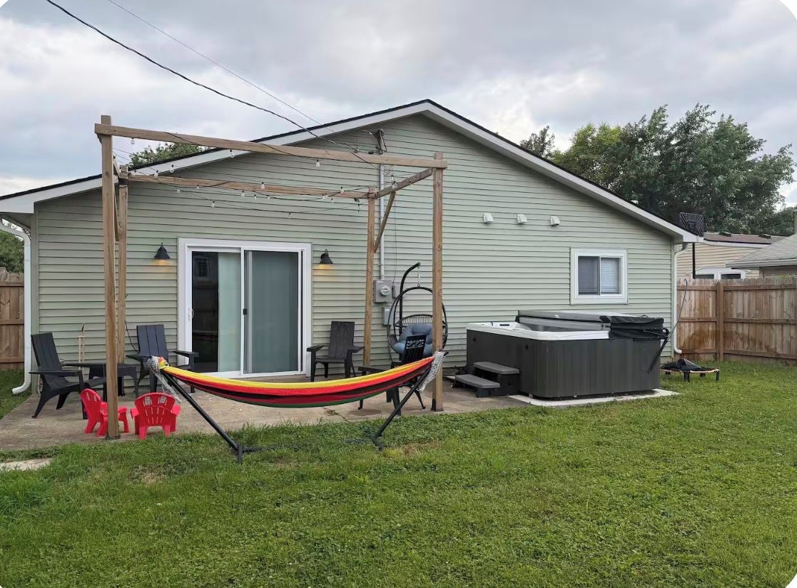 A house with a patio area, outdoor seating, and a hot tub.