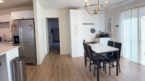 Una cocina moderna con refrigerador de acero inoxidable, piso de madera y un comedor con mesa y sillas.