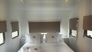 A modern hotel room with a large bed, bedside lamps, and a ceiling air conditioner.