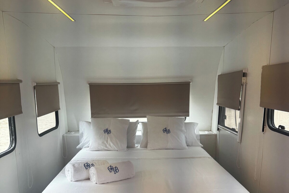 A modern hotel room with a large bed, bedside lamps, and a ceiling air conditioner.
