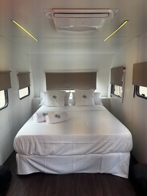 A modern hotel room with a large bed, bedside lamps, and a ceiling air conditioner.