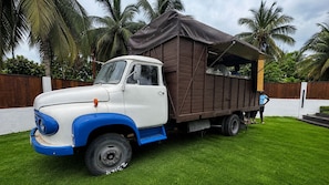 A vintage truck with a covered cargo area parked on a grassy lawn.