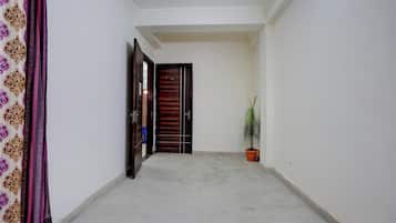 Un pasillo con una puerta de madera, una planta en maceta y una cortina estampada.