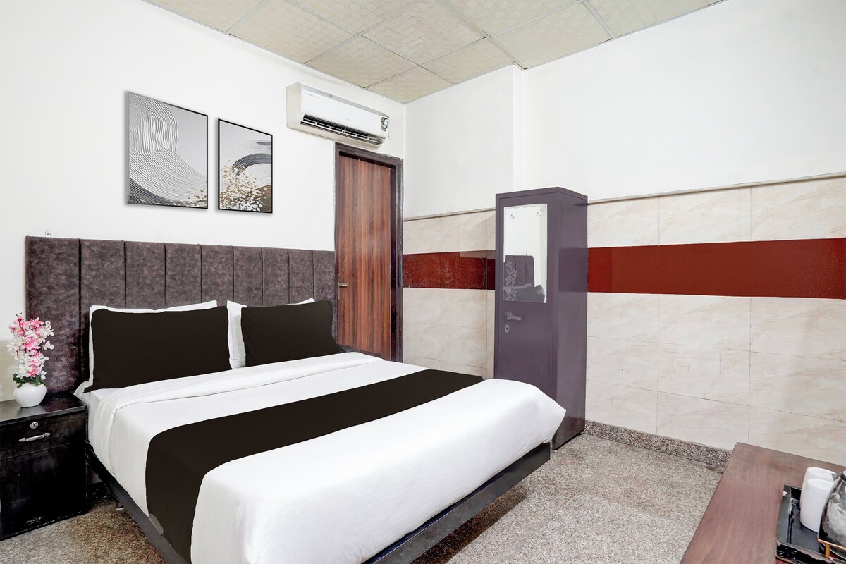 Een hotelkamer met een bed, nachtkastje, dressoir en spiegel.