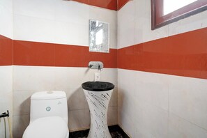 Een badkamer met een wit toilet, een zwarte wastafel en rode en witte betegelde wanden.