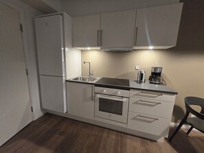 Eine kleine Küche mit Kühlschrank, Herd, Spüle und Kaffeemaschine.