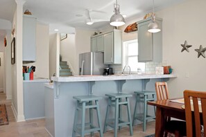 A kitchen with a central island, bar stools, and a dining table with chairs. - 🏖️Beachfront with Gulf Views | Multiple Decks | Outdoor Shower | Summer Salt🏖️ (Cape San Blas)