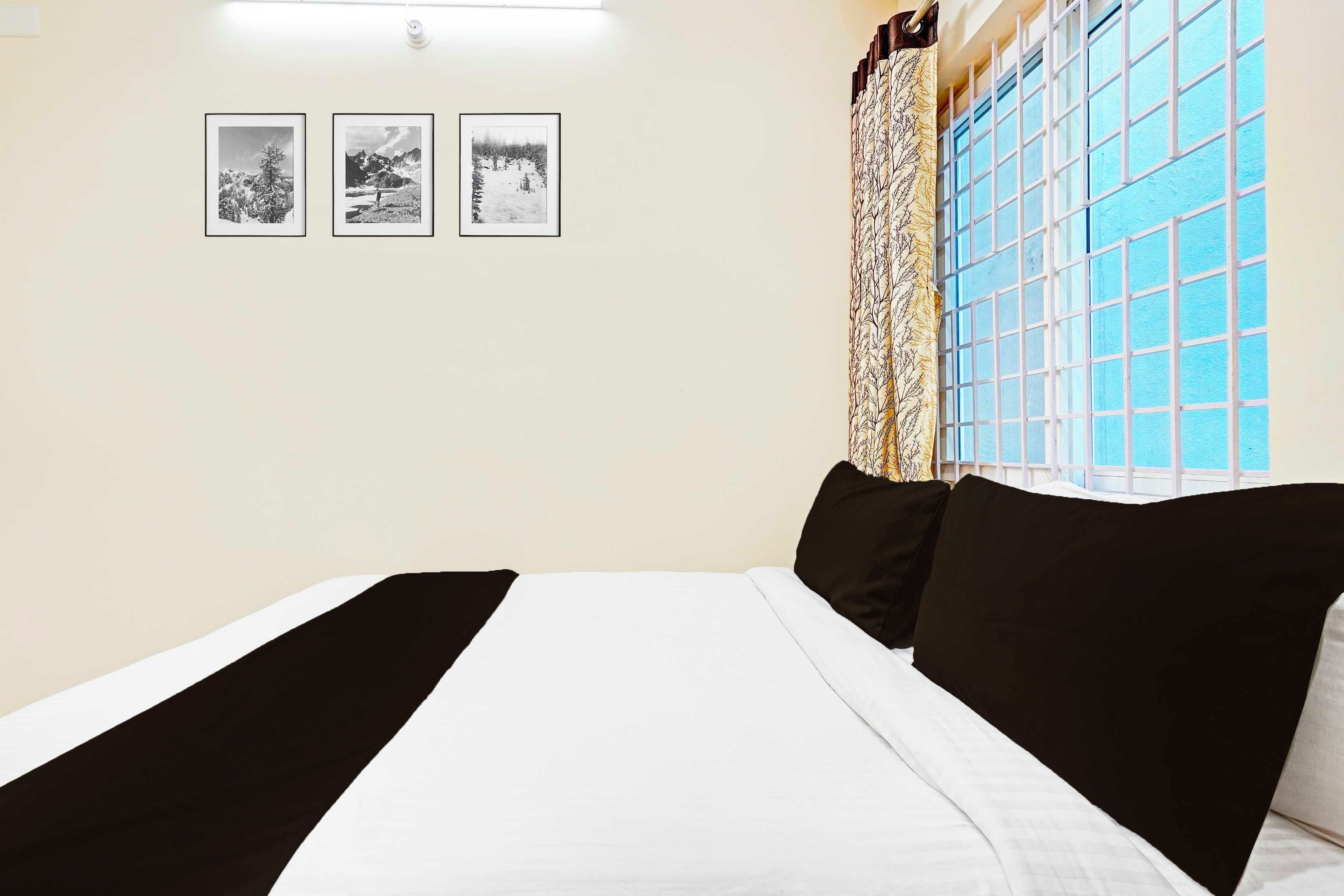 Un dormitorio con una cama, un ventanal con vistas y tres cuadros en la pared.