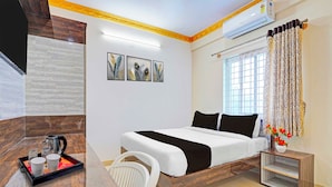 Une chambre d’hôtel comprenant un lit, un bureau avec une machine à café, une chaise, une fenêtre avec des rideaux et des œuvres d’art murales.