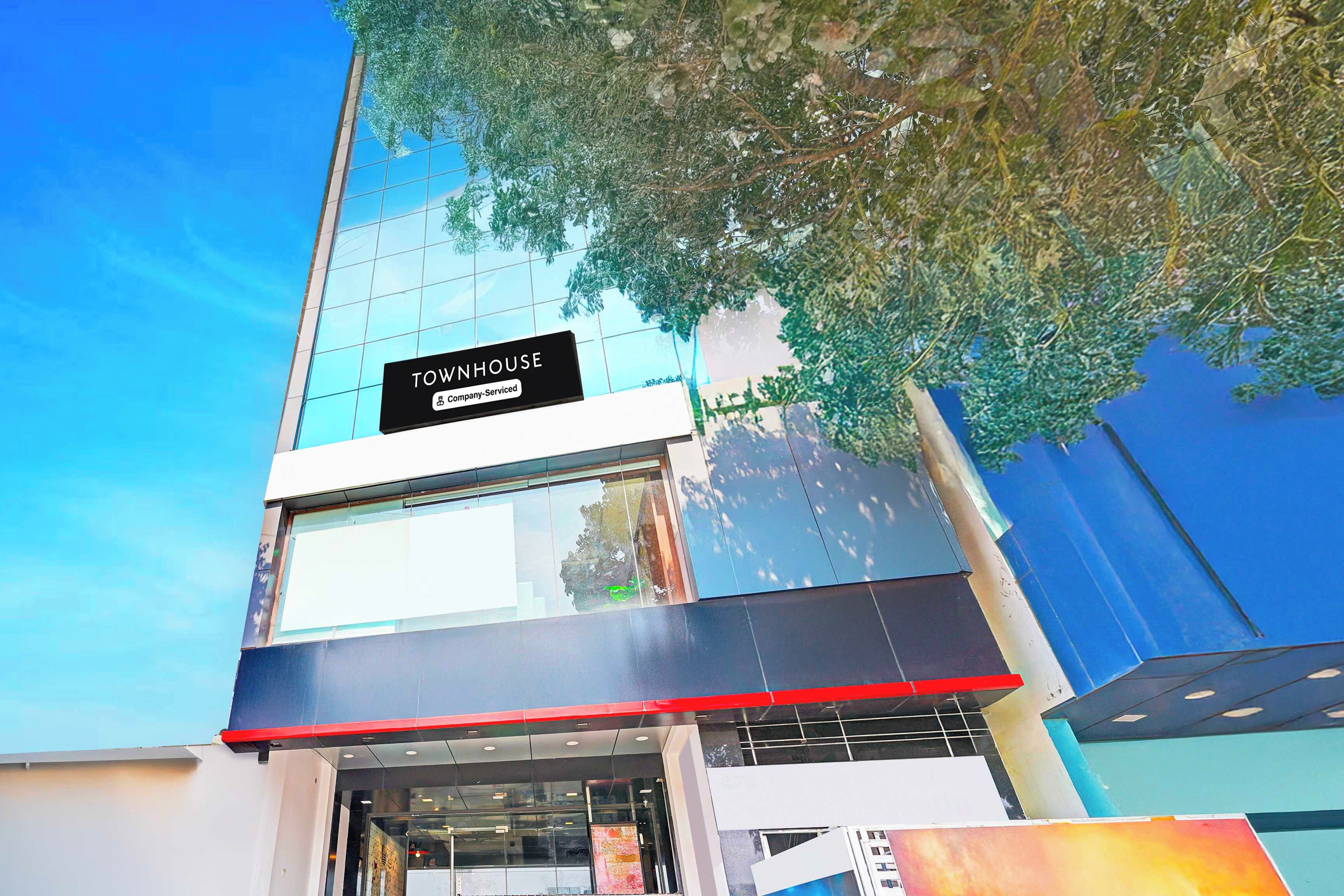 Un edificio moderno con fachada de vidrio y un cartel que dice 'TOWNHOUSE Company-Serviced'.