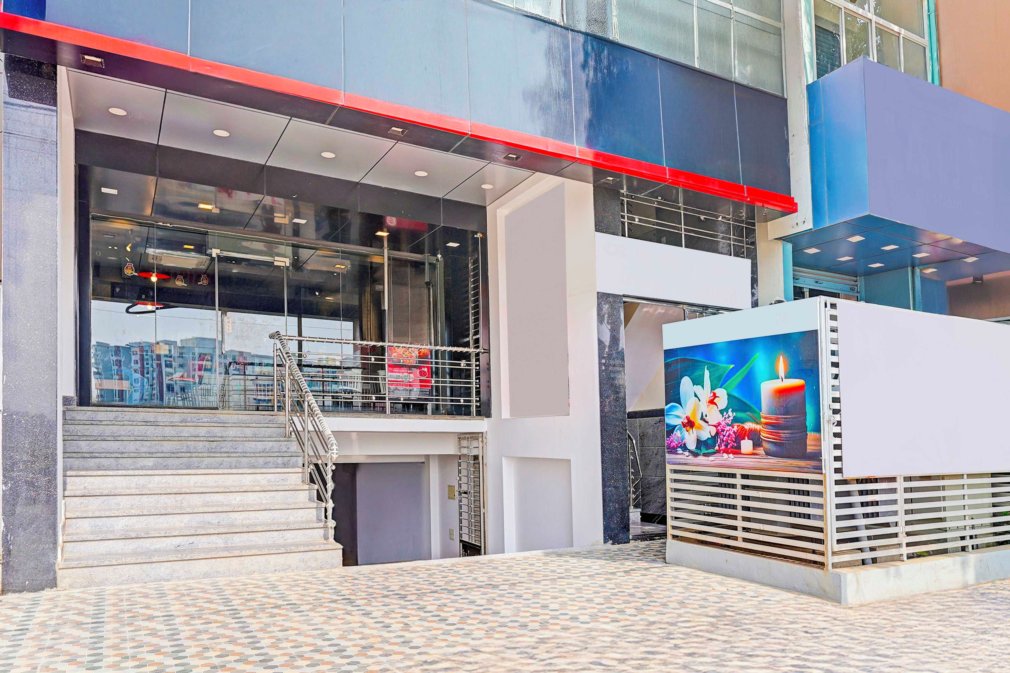 A modern building with a glass facade, a staircase leading to an upper level, and a colorful mural on the exterior wall.