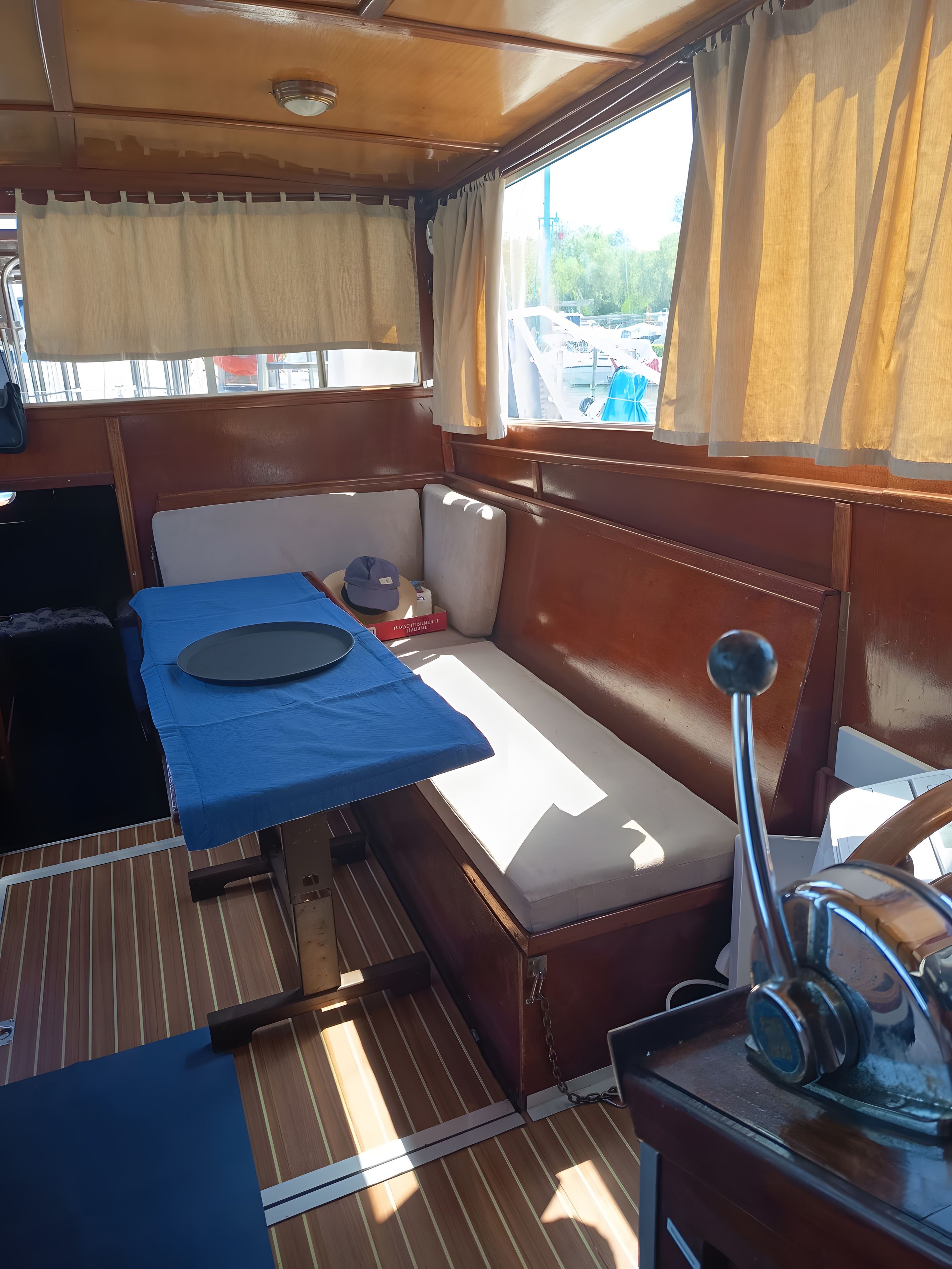 A compact cabin with a small table, a bench, and a steering wheel.