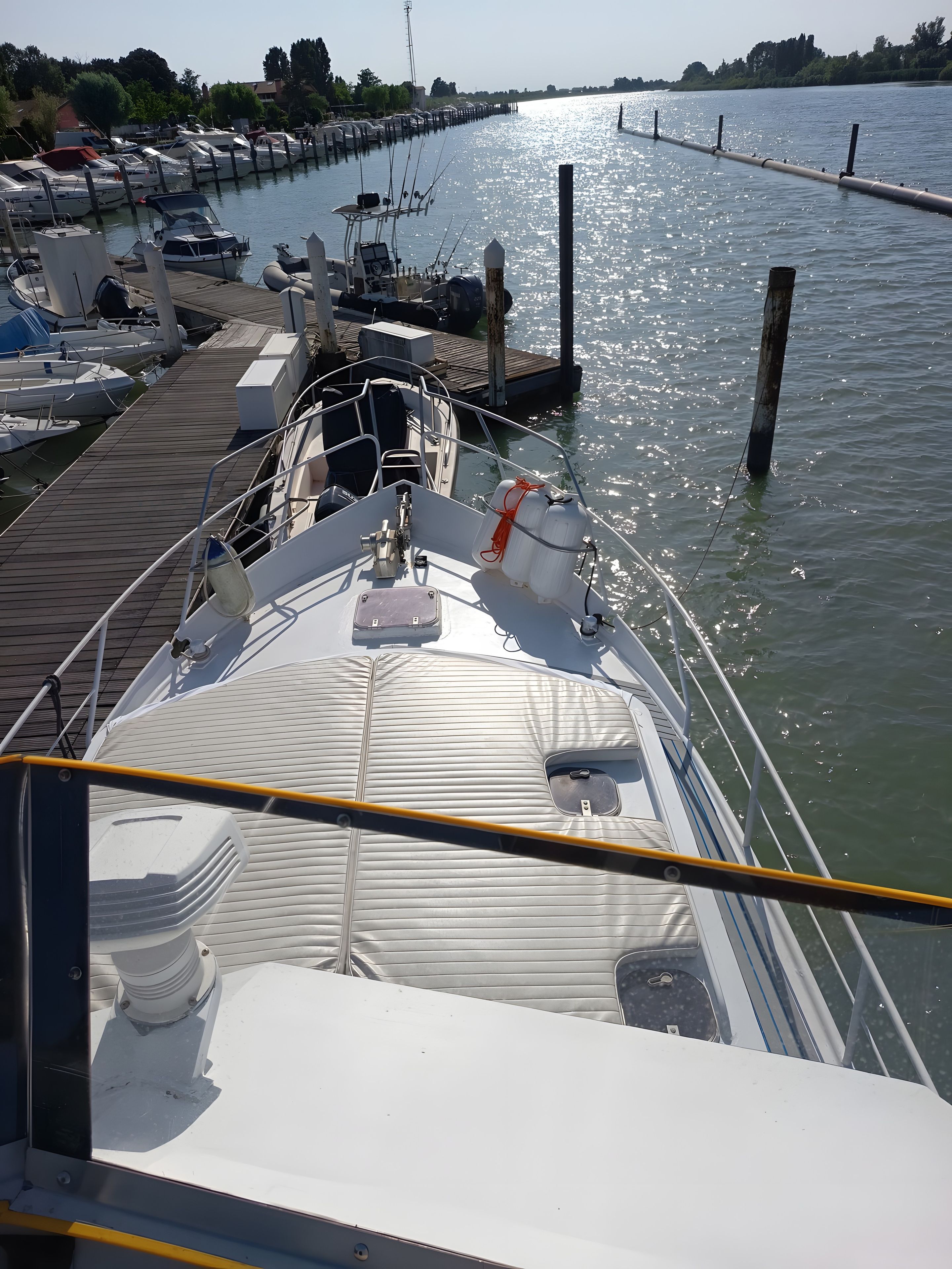 Een jachthaven met afgemeerde boten, een houten looppad en een helder uitzicht op het water.