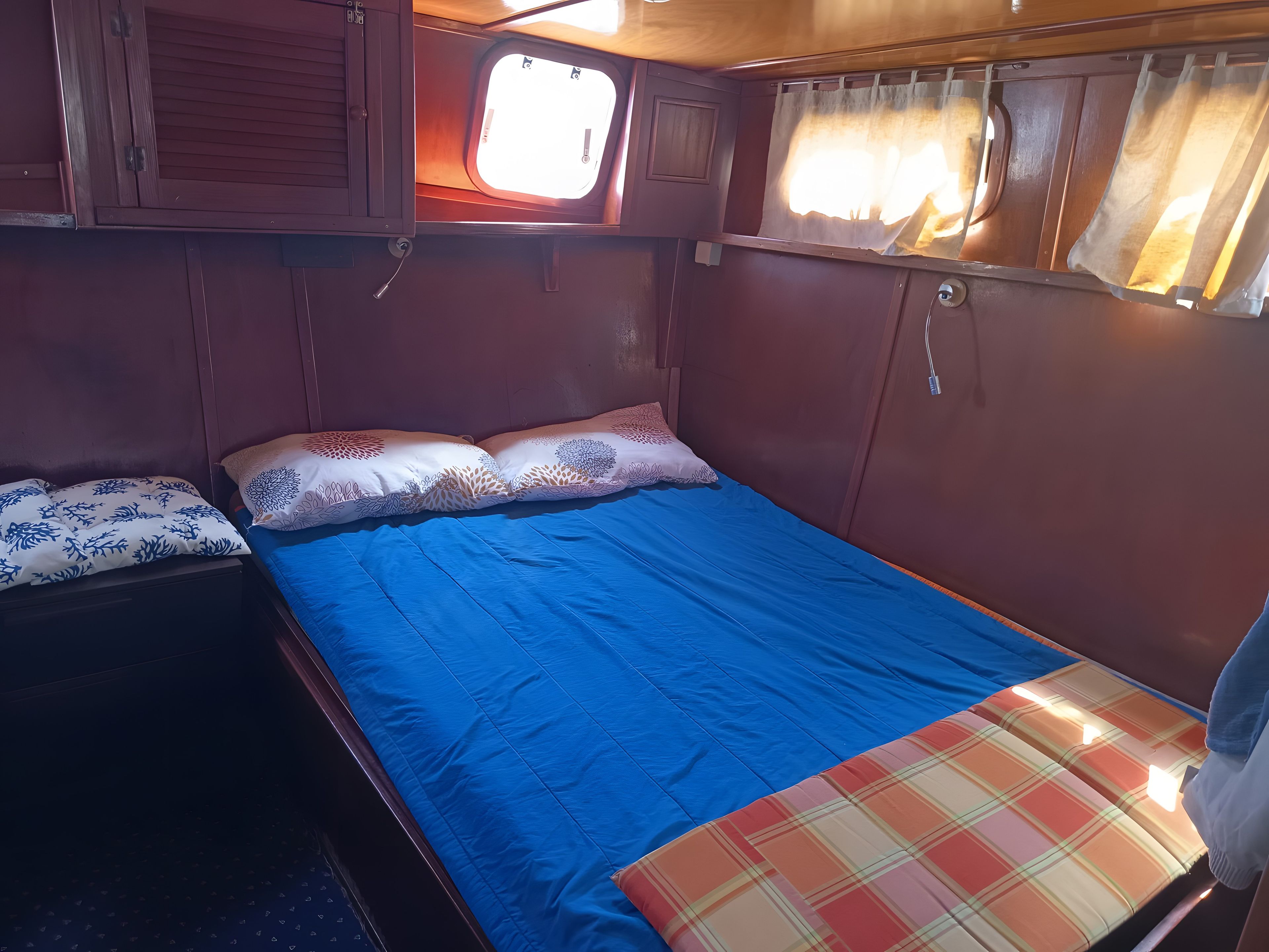 A small, cozy room with a single bed, a window with curtains, and a wooden cabinet.