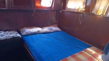 A small, cozy room with a single bed, a window with curtains, and a wooden cabinet.