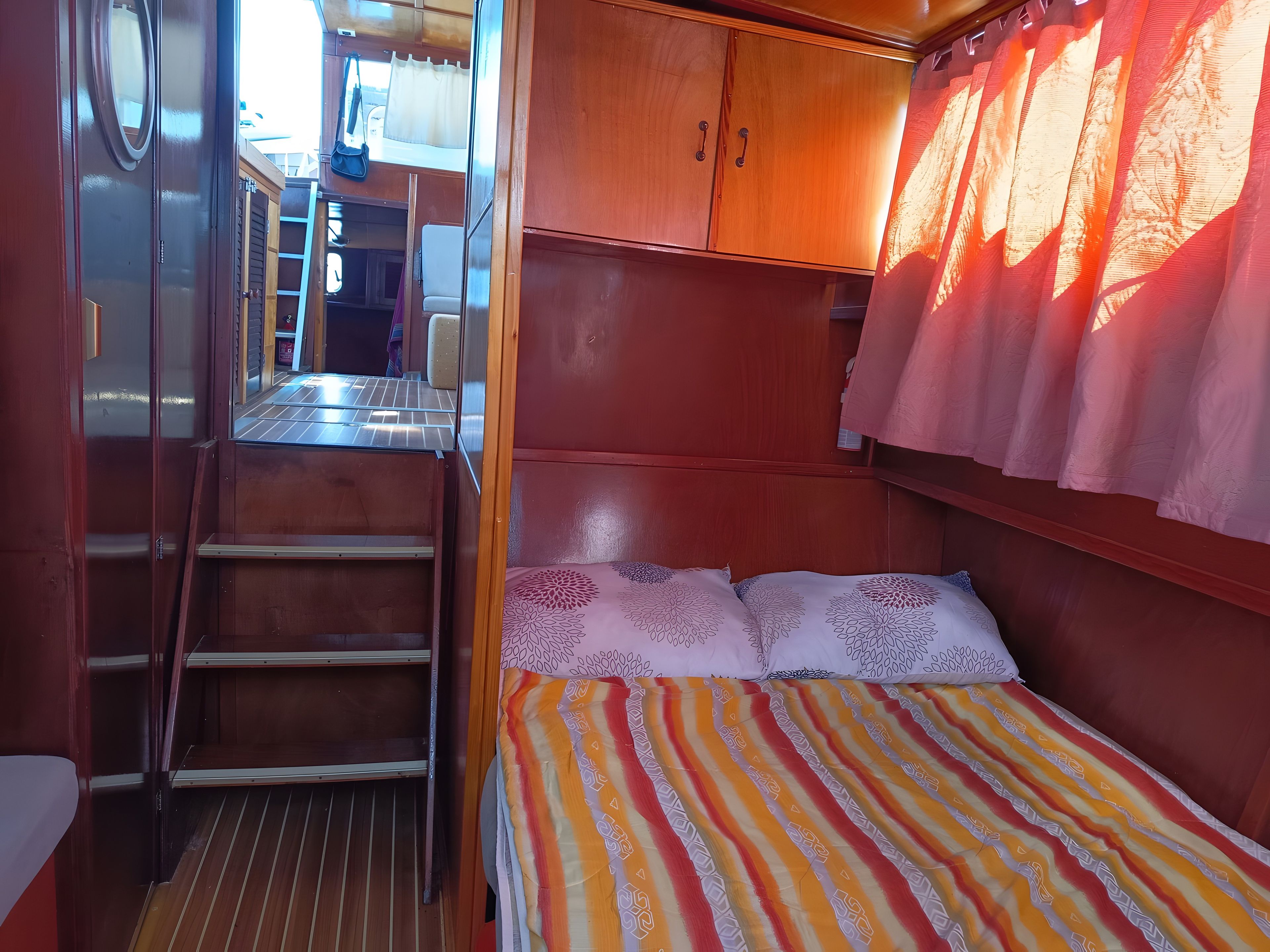 Een compacte ruimte met een bed, een kleine kitchenette en een raam met gordijnen.