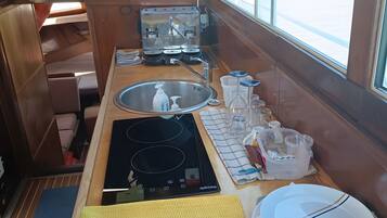 Cocina compacta con un lavamanos, estufa y ventana con vistas al exterior.