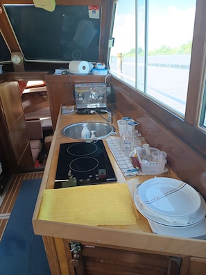 A compact kitchen with a sink, stove, and a window offering a view of the outside.