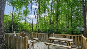 Une terrasse en bois avec des tables de pique-nique et une clôture en bois.