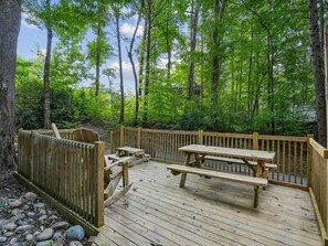 Une terrasse en bois avec des tables de pique-nique et une clôture en bois.