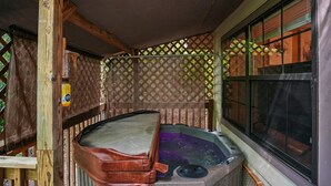 Un bain à remous avec une terrasse en bois et une fenêtre équipée de stores.