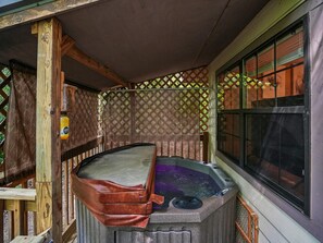 Un bain à remous avec une terrasse en bois et une fenêtre équipée de stores.