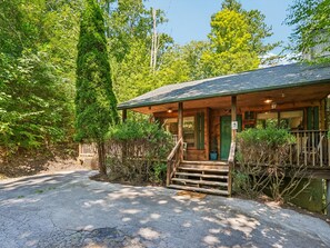 A cabin with a porch, steps leading up to the entrance, and a view of the surrounding forest. - Bear Crest | Hot Tub, Pet-Friendly (Gatlinburg)