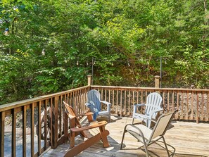 Um deck de madeira com cadeiras Adirondack e uma guirlanda de luzes.