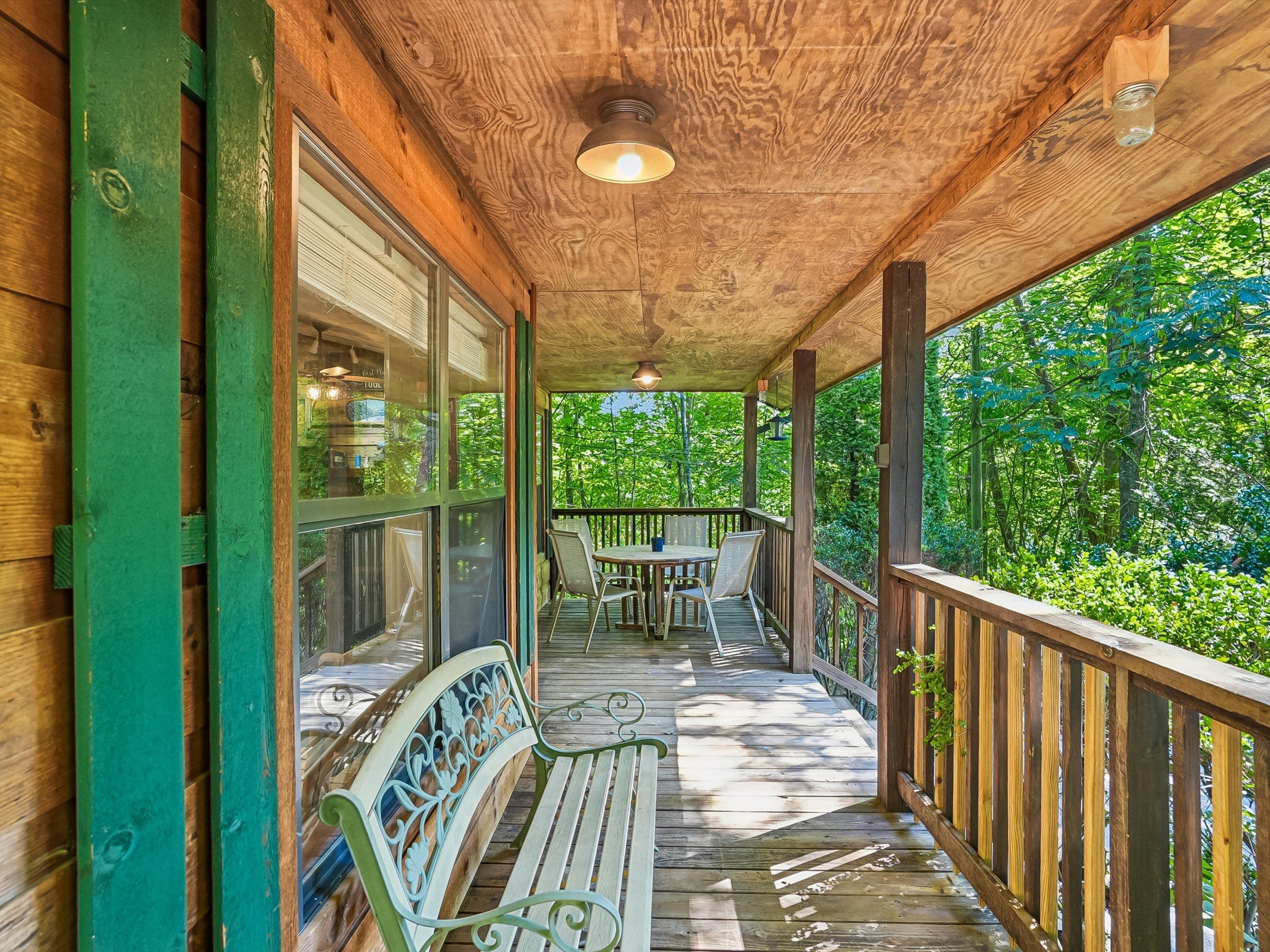 A wooden deck with a table and chairs, surrounded by glass walls and a bench.