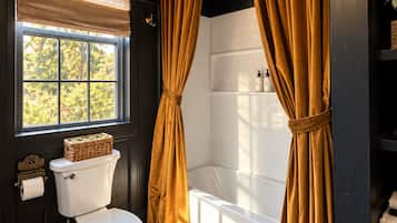 A bathroom with a toilet, a window with a blind, a bathtub, and a shower curtain.
