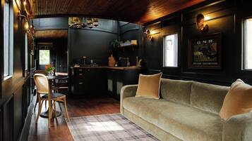 A cozy room with a sofa, a dining table, and a kitchen area.