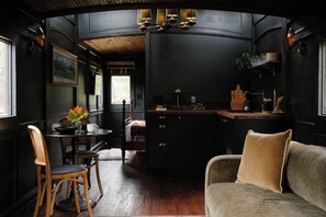 A compact, dark-themed interior with a dining area, a sofa, and a kitchen counter.