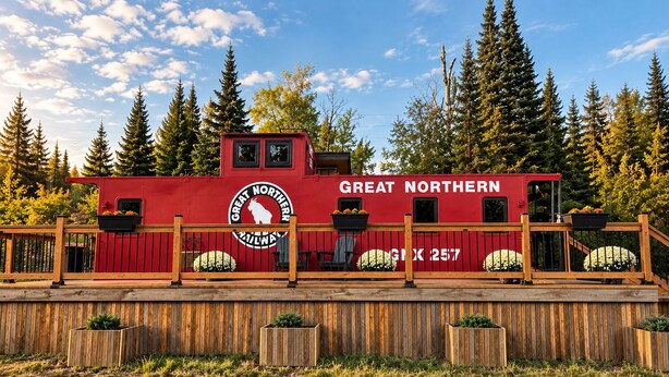 En rød bygning med 'GREAT NORTHERN' skilte, en træterrasse og en skov i baggrunden.
