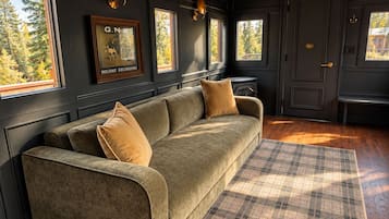 A room with a sofa, a plaid rug, and framed pictures on the wall.