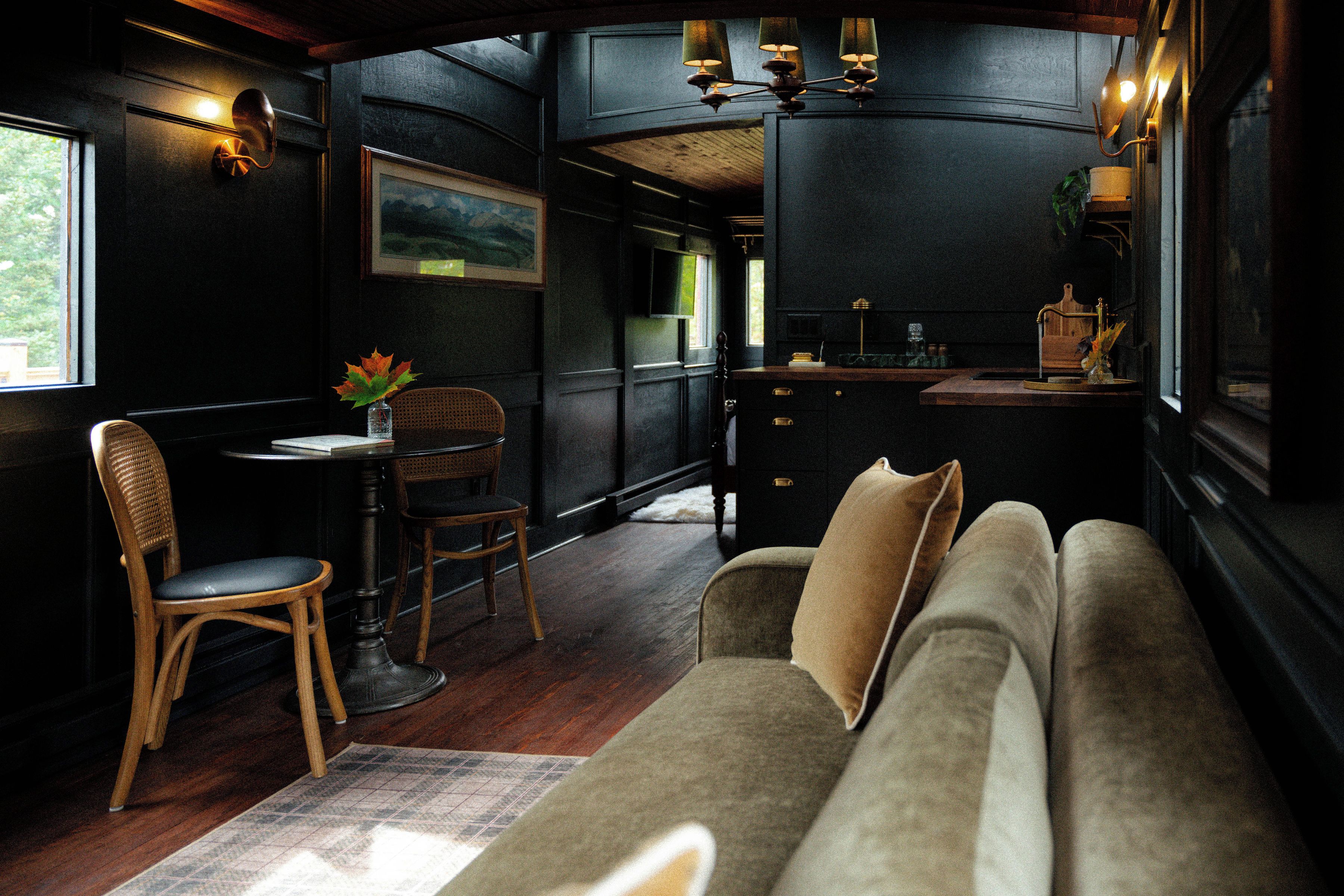 A cozy interior with a sofa, dining table, chairs, and a kitchen area.