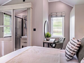 A bedroom with a bed, a desk, a chair, a mirror, and a window with blinds. - Prion 1.0 Spa (Denbigh)