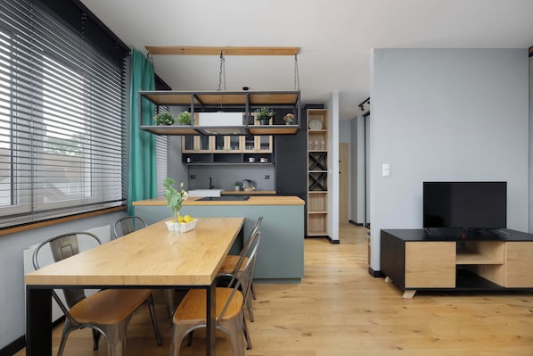 Cozinha moderna com mesa de jantar de madeira, cadeiras e um aparador para TV.