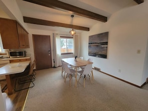 A dining area with a table and chairs, a microwave, and a door leading to another room. - Century Noll | Whole Duplex, 3BR, Yard, Pets, Mayo (Rochester)