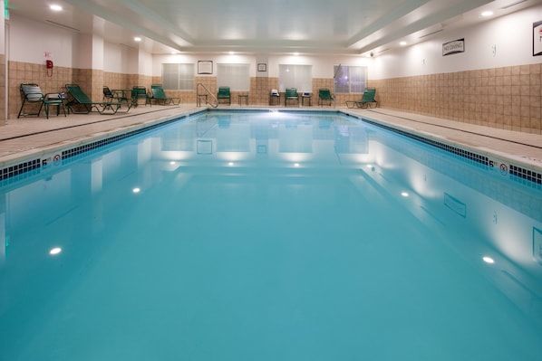 Uma piscina coberta ampla com espreguiçadeiras e um aviso de 'NÃO MERGULHAR'.
